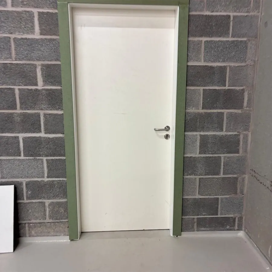 Porte blanche posée dans une huisserie verte